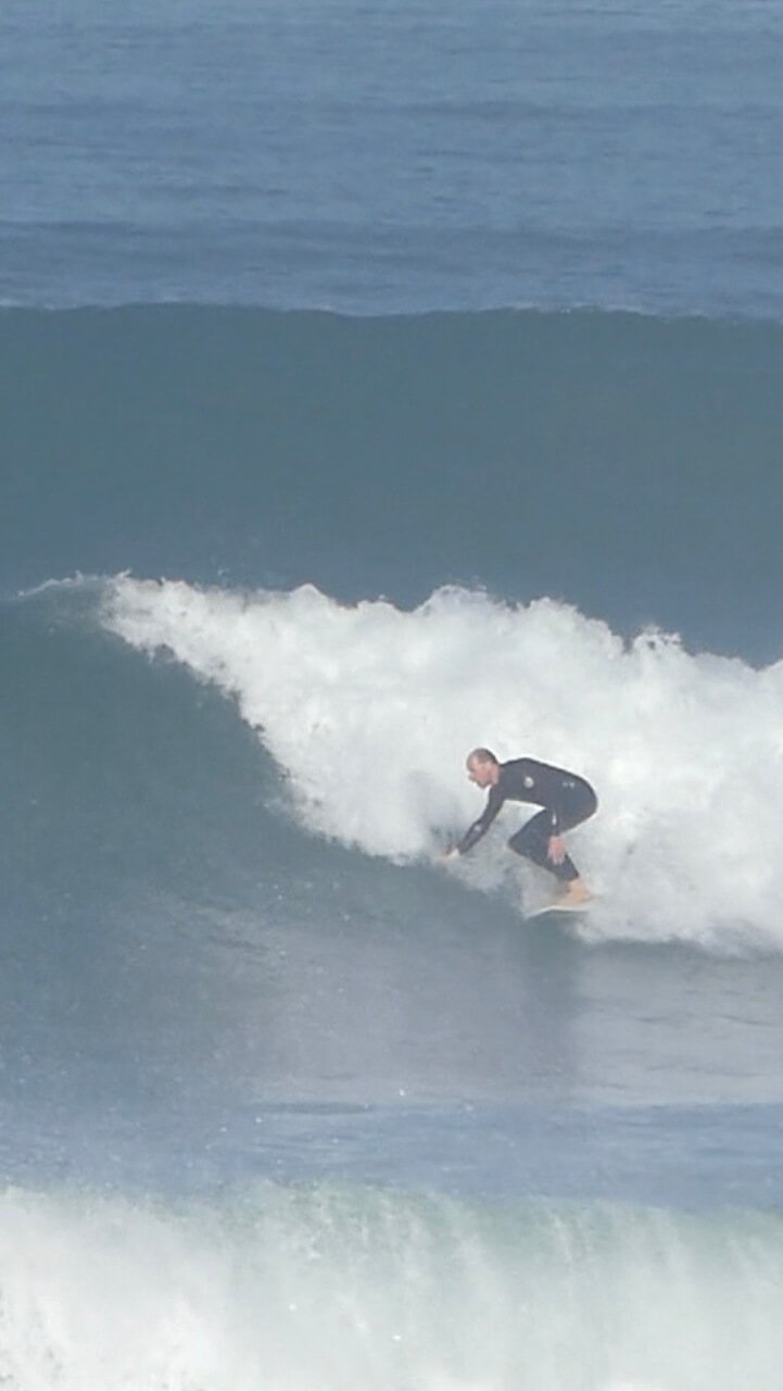 An intermediate surfer practicing a technical bottom turn under the expert guidance of Filipe Anjos during a private coaching session in Peniche.